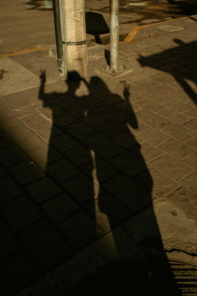 Silhouettes of two people casting shadows on urban pavement in sunlight.